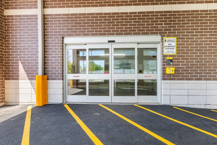 Sliding glass entry doors at a Safeguard Self Storage facility with a keypad and yellow parking lines